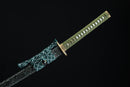 A close-up view of Kyojin Katana, with a green handle and black shealth on a wooden stand.