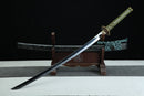 A close-up view of Kyojin Katana, with a green handle and black shealth on a wooden stand.