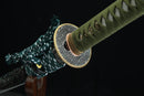 A close-up view of Kyojin Katana, a green sword with a decorative handle, against a black background.