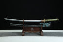 A close-up view of Kyojin Katana, with a green handle and black shealth on a wooden stand.