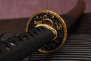 A photo of Moonswords Kyoyu Katana in black, with a bronze guard, is shown against a dark, slatted bamboo mat background.