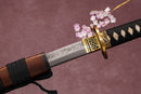A close-up view of Moonswords Kyoyu Katana with Hamon on the blade and intricate brown and gold designs on the handle.