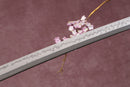 A close-up view of a clay-tempered T10 steel blade against a textured background