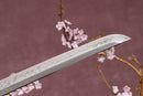 A close-up view of a clay-tempered T10 steel blade against a textured background