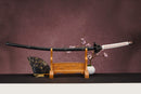 A photo of Moonswords Black mortal blade, Kaimon Odachi with an aged bronze guard, is shown against a dark background.