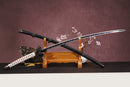 A close-up view of Moonswords Black mortal  blace Odachi, with a green handle and black accents, featuring intricate designs and patterns.