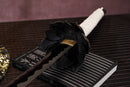 A photo of Moonswords Black mortal blade, Kaimon Odachi with an aged bronze guard, is shown against a dark background.