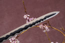 A close-up view of a Damascus steel blade against a textured background