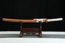 A close-up view of Nichirin Katana, with a white handle and orange shealth on a wooden stand.