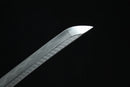 A close-up view of a Clay-Tempered Damascus Steel blade against a black background.