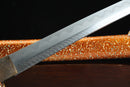 A close-up view of a Clay-Tempered Damascus Steel blade against a black background.