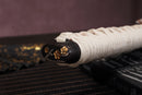 Close-up of Moonswords Nichirin katana handle with intricate designs on a textured surface.