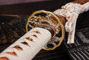 A photo of Moonswords Nichirin Katana with a bronze guard, is shown against a dark, slatted bamboo mat background.