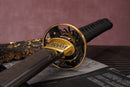 A photo of Moonswords Ryokuya Ichirin Katana in green, with a bronze guard, is shown against a dark, slatted bamboo mat background.