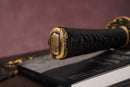 Close-up of Moonswords Seima Guren katana handle with intricate designs on a textured surface.