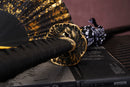A photo of Moonswords Seima Guren Katana in black, with a bronze guard, is shown against a dark, slatted bamboo mat background.