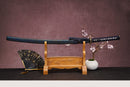 A single katana with a deep blue handle and white accents on the stand is shown against a textured background.