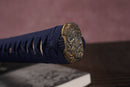 Close-up of Moonswords Shuen no Bara katana handle with intricate designs on a textured surface.