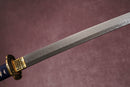A close-up view of a Damascus blade with textures against a textured background.