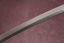 A close-up view of a Damascus blade with textures against a textured background.