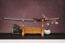 A single katana with a brown handle and white accents on the stand is shown against a textured background.