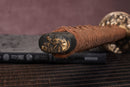 Close-up of Moonswords Shunsho katana handle with intricate designs on a textured surface.
