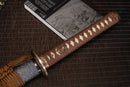 A close-up view of Moonswords Shunsho Katana with bronze guard, brown handle and grey shealth.