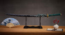A close-up view of Moonswords Suiha Katana, with a green handle and black accents, featuring intricate designs and patterns.