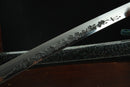 A close-up view of a Clay-tempered Tamahagane Steel blade against a dark background.