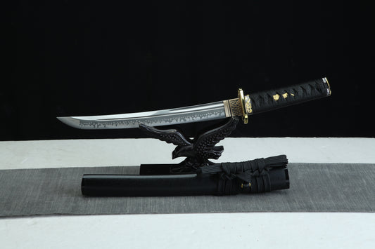 TANTO Sword Damascus Steel Blade with a black sheath on a gray surface against a black background