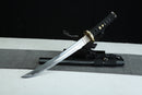 A Japanese-style sword with a black handle and gold accents is displayed on a black surface, with a gray cloth underneath.