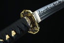 A close-up view of a decorative sword handle with intricate gold and black designs.