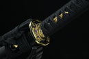 A close-up view of a black and gold sword blade with intricate designs and patterns.