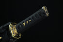 A close-up view of a black and gold sword handle with intricate designs and patterns.