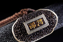 Close-up of the engraving on the black shealth of the Qianqing sword against a black background