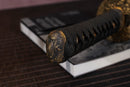 Close-up of Moonswords Toga wakizashi handle with intricate designs on a textured surface.