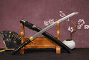 A close-up view of Moonswords Toga Wakizashi, with a black handle and white accents, featuring intricate designs and patterns.