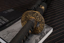 A photo of Moonswords Toga Wakizashi in black, with a bronze guard, is shown against a dark, slatted bamboo mat background.