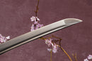A close-up view of a sharp, pointed Damascus steel blade with textures against a textured background.