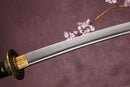 A close-up view of a sword with a bronze hilt and a Damascus steel blade, set against a textured background.
