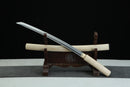 Sword with white handle on a wooden stand against a black background