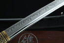 A close-up view of a sword with a dripping or dripping-like pattern along its blade, resting on a wooden surface.