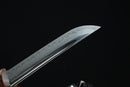 A close-up view of a sharp, curved blade of a knife against a dark background.