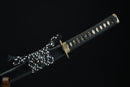 A close-up view of a black and gold sword with a decorative handle, displayed against a black background.