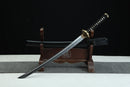 A Japanese-style sword with a black handle and gold accents is displayed on a wooden stand against a black background.